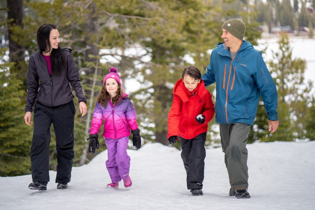 Family walking through the snow, the son has a snowball