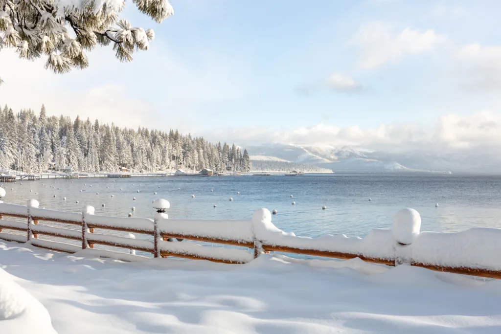 A winter landscape in Lake Tahoe with snow-dusted trees, sky, and lake. Winter activities in Lake Tahoe.