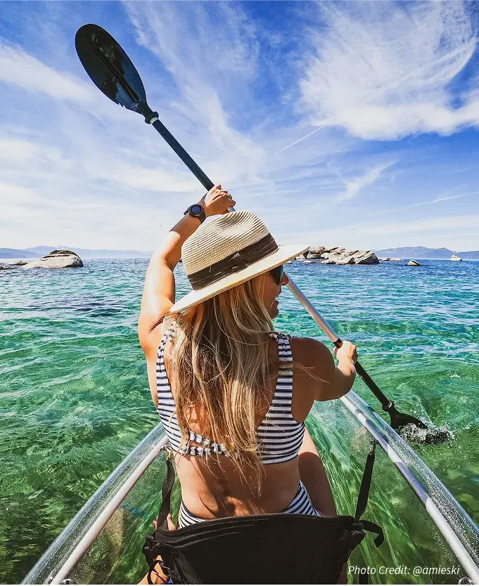 Woman with blonde hair kayaking on the crystal green waters of Lake Tahoe