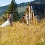 Couple in a field next to an old barn on their wedding day