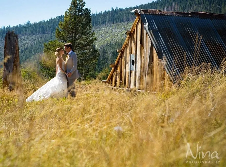 Couple in a field next to an old barn on their wedding day