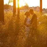 Couple embracing at sunset on their wedding day in tall grass