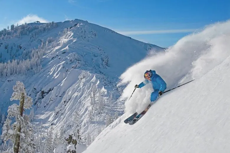 Person skiing down a powdery slops carving in deep