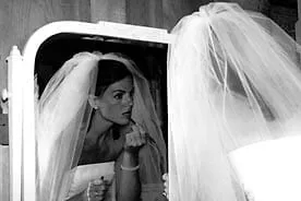 Bride putting on lipstick in the mirror on her wedding day