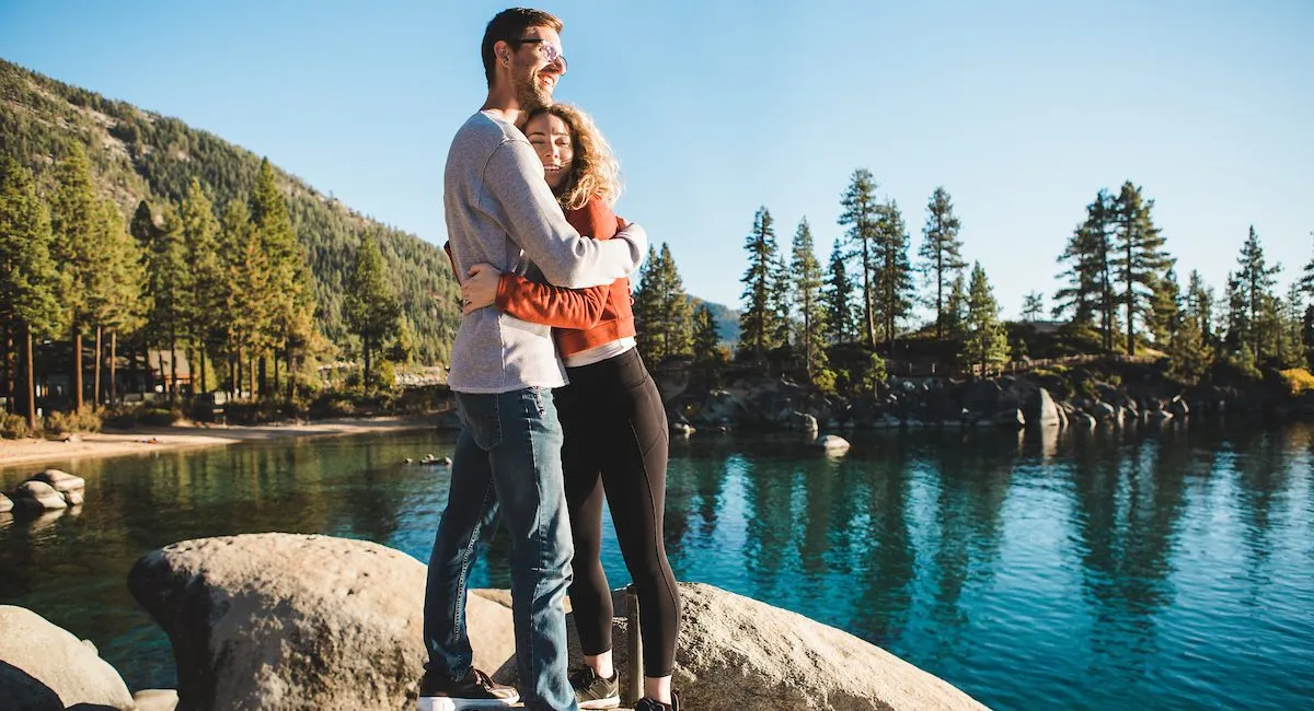 Couple hugging on rocks enjoying Sand Harbor overlooking Lake Tahoe