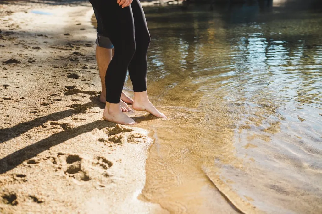 Two people putting their feet in the water on the shores of Lake Tahoe