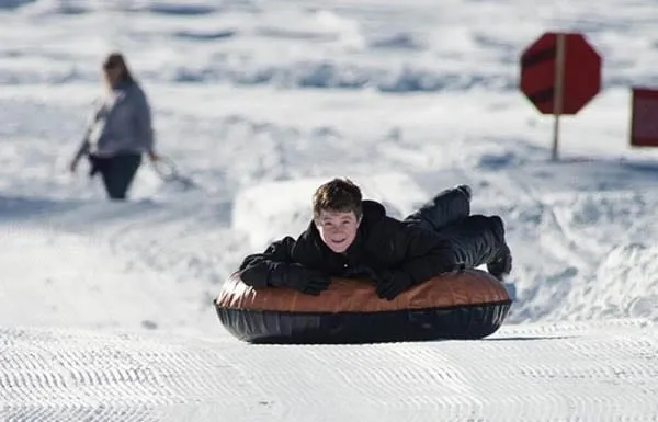 Teenager stubing down a slope on a sunny day at Soda Springs Lake Tahoe