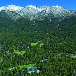 Photo of mountains with green trees at the base and snow at the top in Lake Tahoe