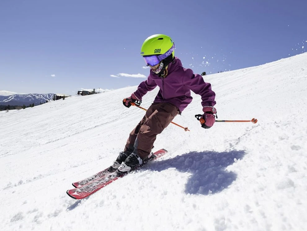 Person skiing down a snowy mountain in a green helmet