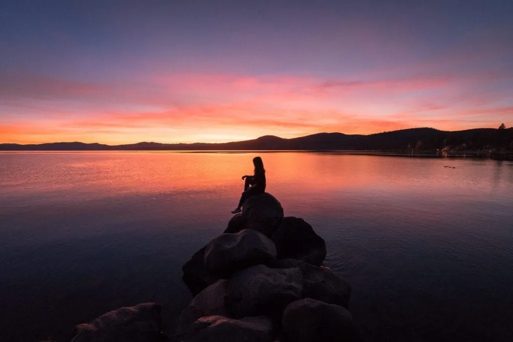 Woman sitting on a rock in Lake Tahoe at dusk