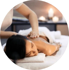 A masseuse massages upper back of relaxed woman laying down on a massage table