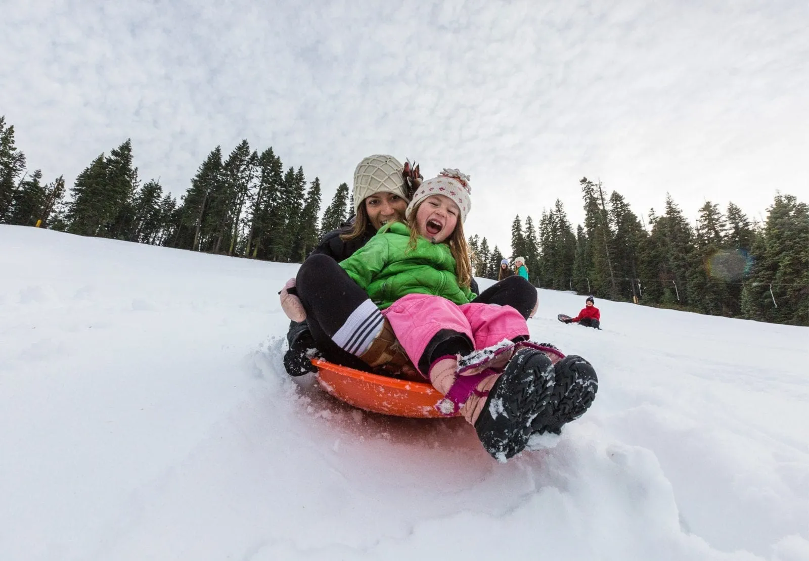 Mom and daughter sledding down the hill in Lake Tahoe
