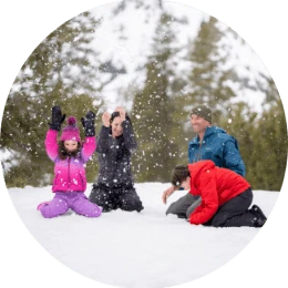 Playful family seated on ground in Lake Tahoe throw snow up into the air