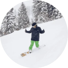 Snowboarder giving thumbs surrounded by snowy evergreen trees in Lake Tahoe during winter