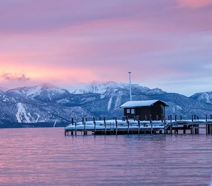 An early evening shot of a snowy Squaw Valley shore with beautiful mountains in the distance and lilac skies.