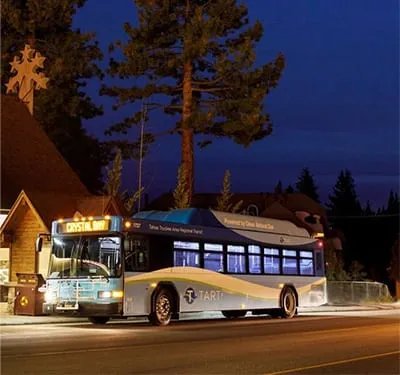 Image of a transit bus at dusk surrounded by trees