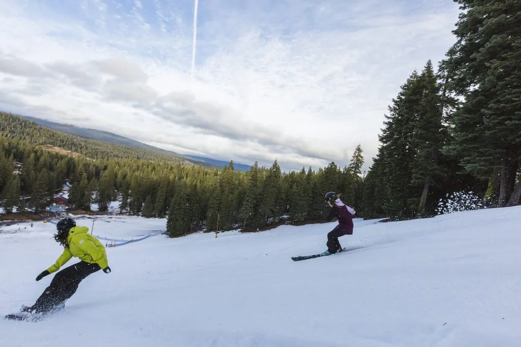 Two people skiing and snowboarding down the mountain
