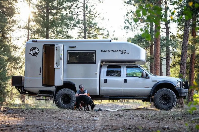Over-lander with his RV and dog in the woods