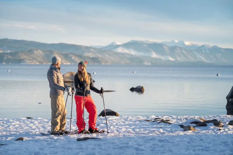 Couple snowshoeing next to the lake in Lake Tahoe 