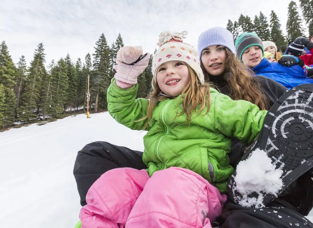 Group of kids sledding down a snowy slope 