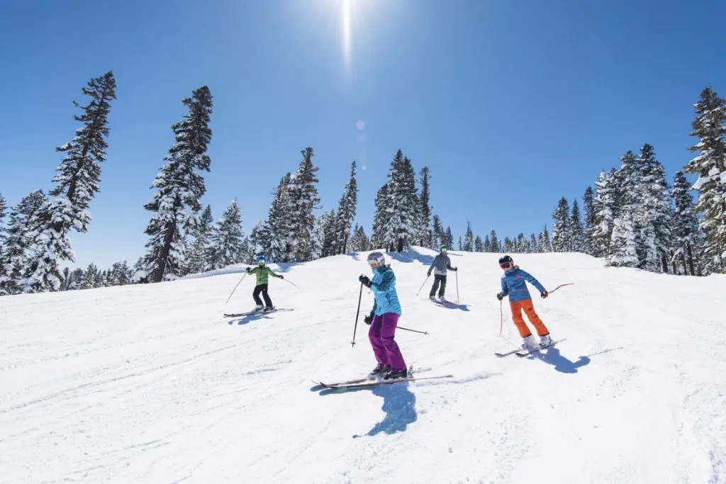 Group of skiers skiing down a snowy hill on a clear day in Tahoe