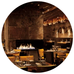 Interior of a fancy restaurant with empty tables and fireplace burning in background