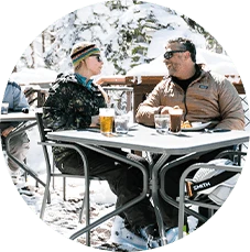 Man and woman talk during casual dinner at restaurant in snowy Lake Tahoe winter setting