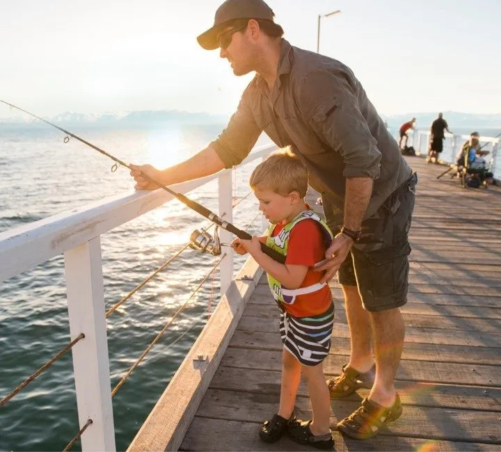 Father helping son go fishing in Lake Tahoe off pier