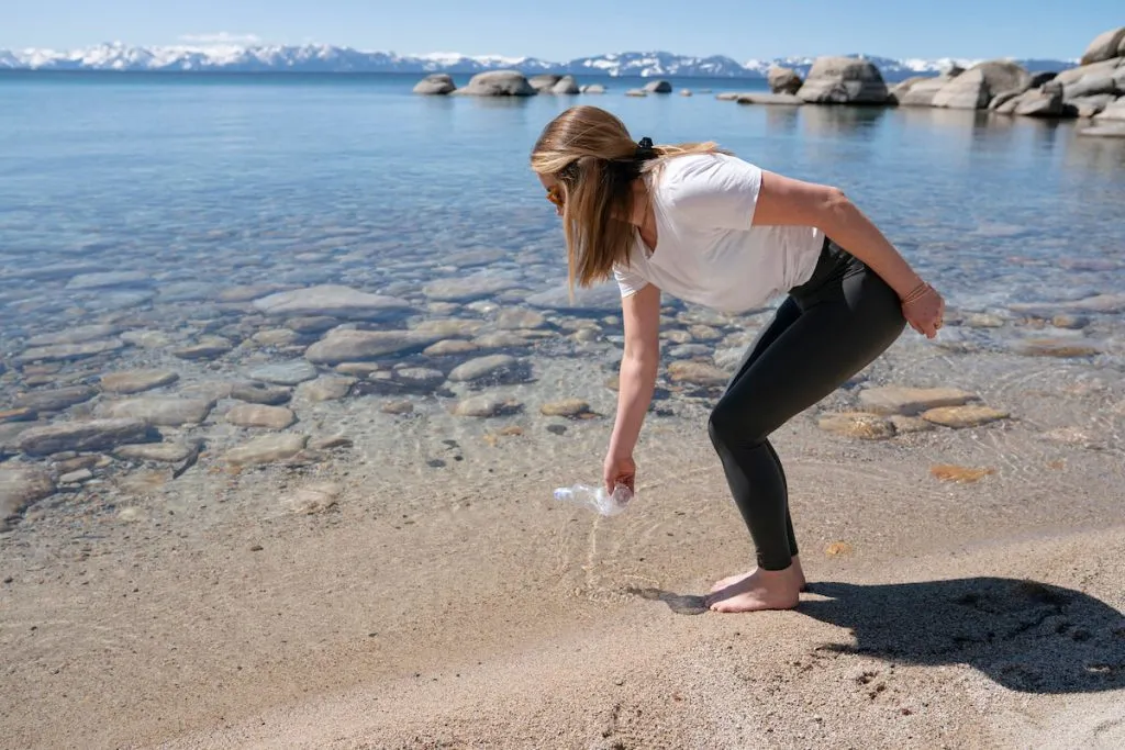 Woman picking up a water bottle on the beaches of Lake Tahoe