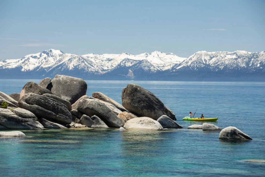 Kayaking in Lake Tahoe with snowy mountain in the background.