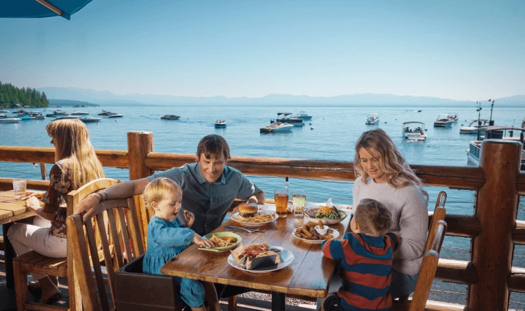 Outdoor dining in North Lake Tahoe with couple enjoying lunch on a snowy patio surrounded by pine trees