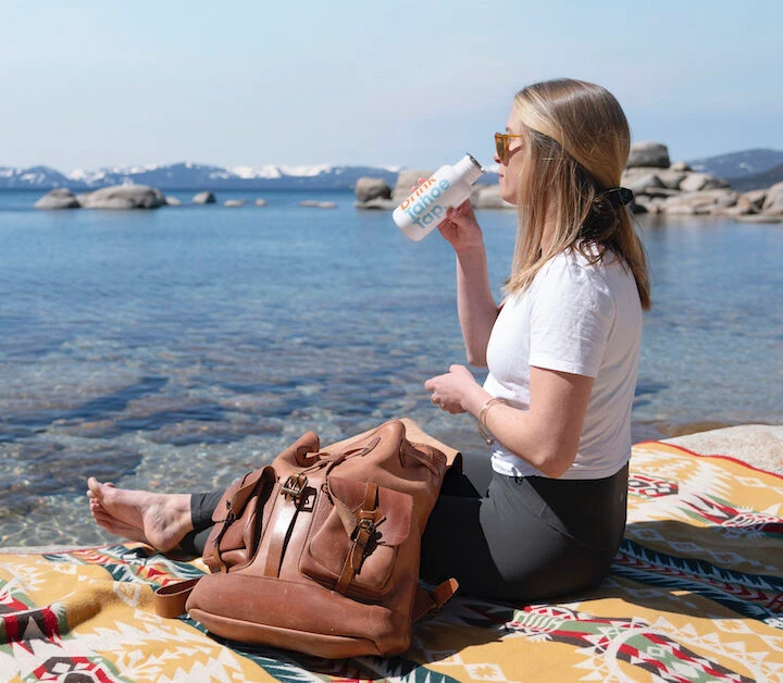 Woman drinking next to Lake Tahoe's clear blue waters