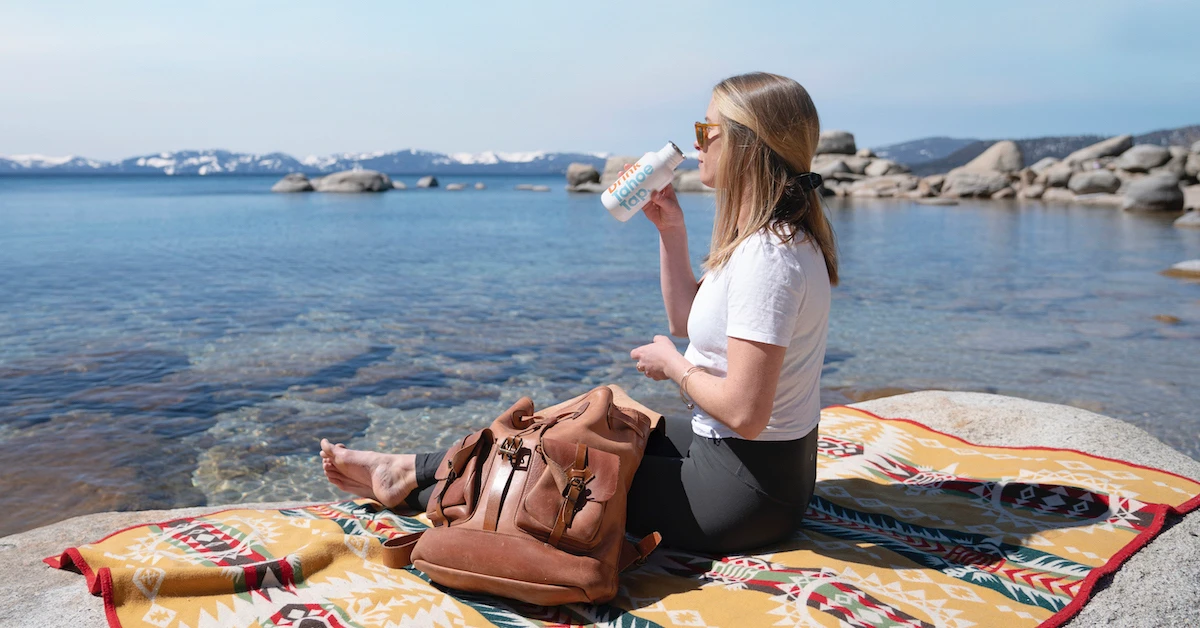 Woman drinking next to Lake Tahoe's clear blue waters
