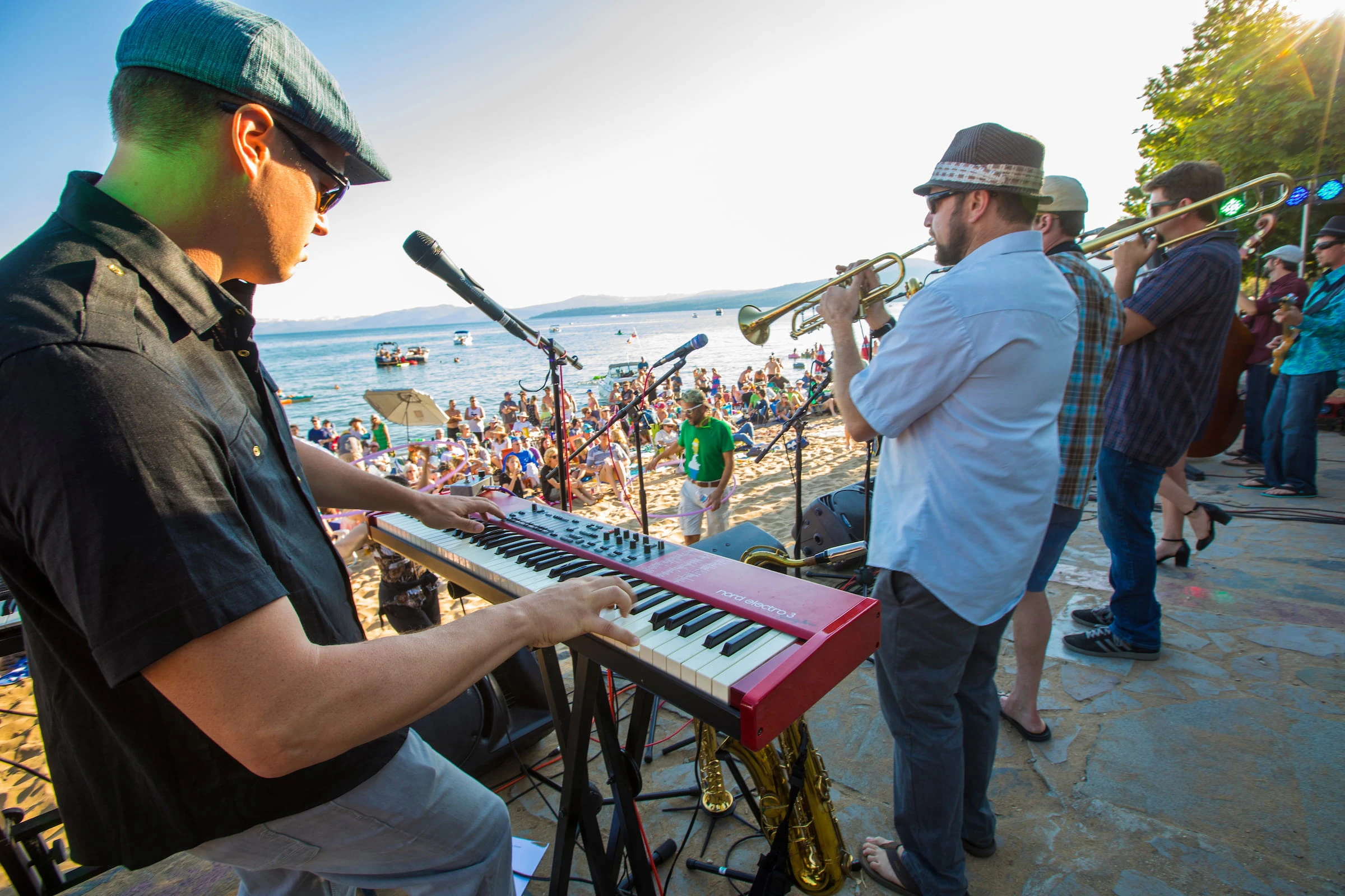 Live band performing at a beachside event with a crowd by the water.